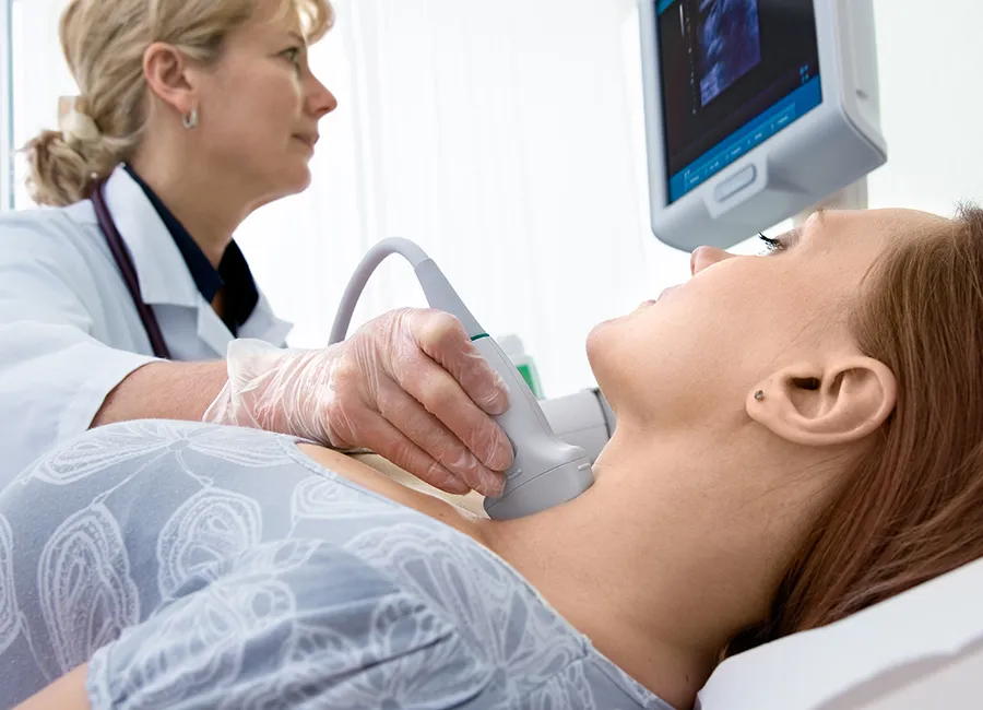A doctor examines a woman's thyroid using ultrasound