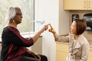 Dr. Kwon testing the motor skills of a patient by touching index fingers.