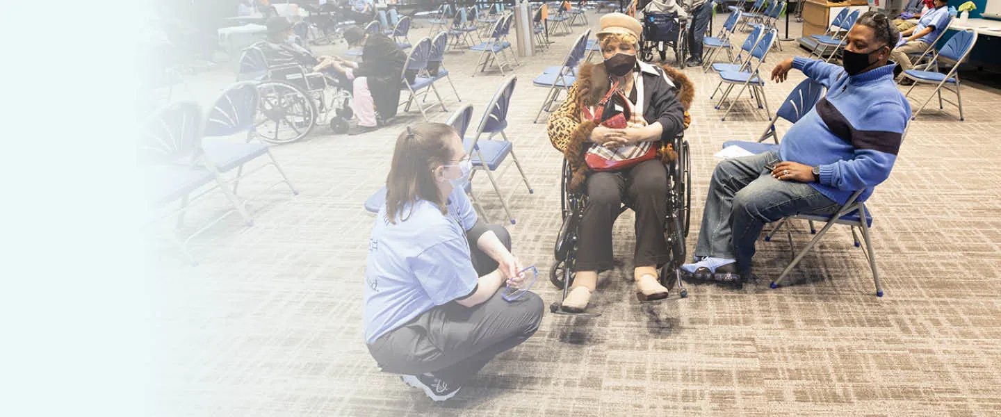 A medical professional speaking with two people at a public clinic