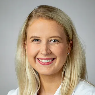 Dr. Wikner Bresnahan has long blonde hair, is wearing a white medical coat, and is smiling at the camera.