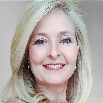 Dr. Caudill has long blonde hair, is wearing a white medical coat and is smiling at the camera