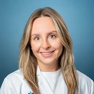 Dr. Gemmiti has long blonde hair, is wearing a white medical coat, and is smiling at the camera.
