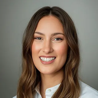 Dr. van Reesema has long brown hair, is wearing a white medical coat, and is smiling at the camera