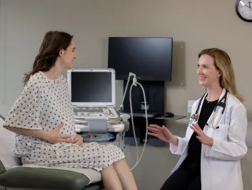 Dr. Robbins smiling with pregnant patient in a doctor's clinic.