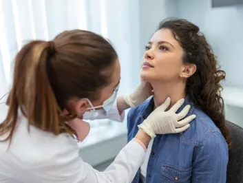 Endocrinologist examining throat of young woman in clinic