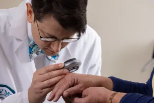 Dr. Enos examining a patients skin.