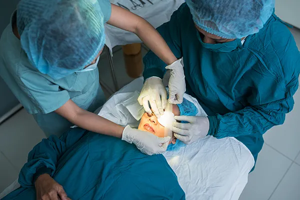 Two surgeons perform surgery on a patient’s eye in an operating room