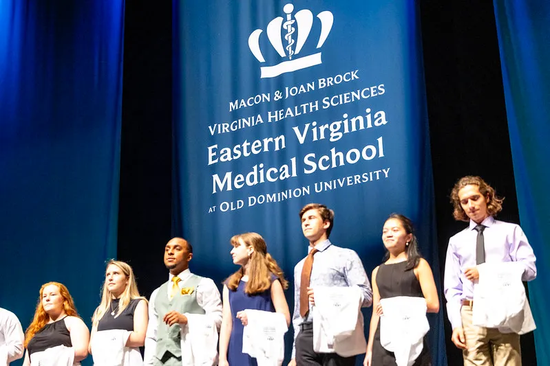 students on a stage with white coats.