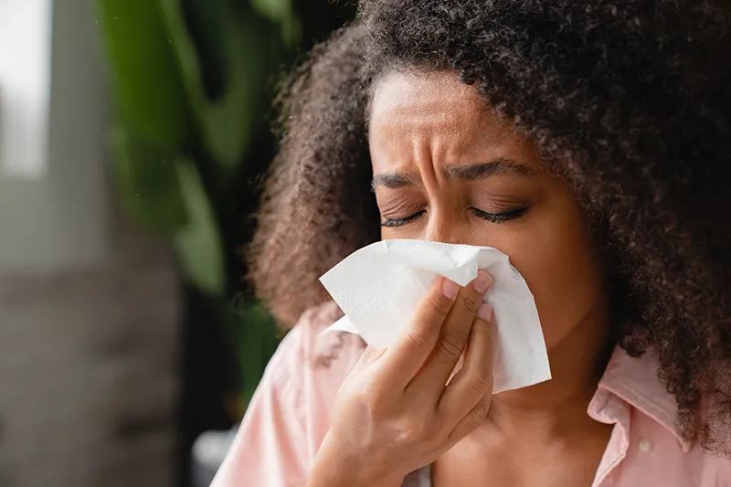 Woman sneezing into tissue