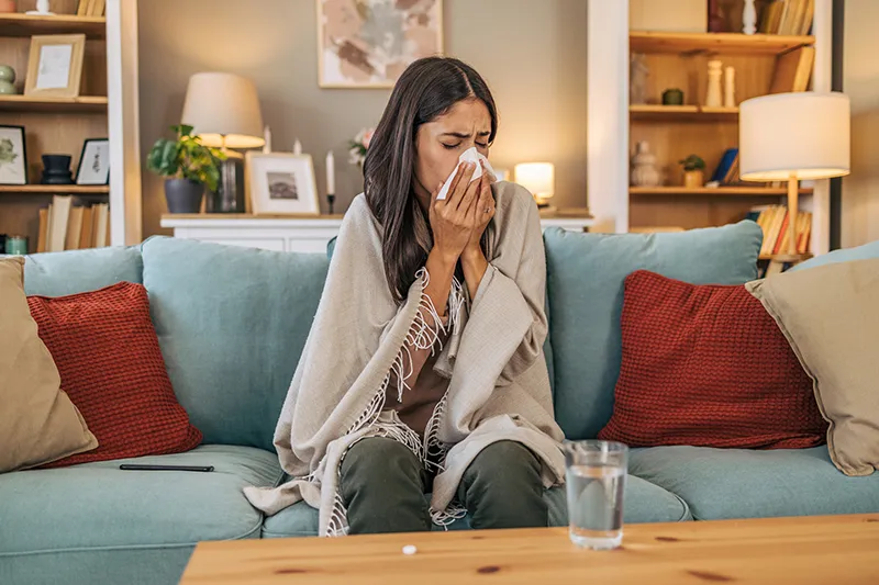 Woman sneezing on couch