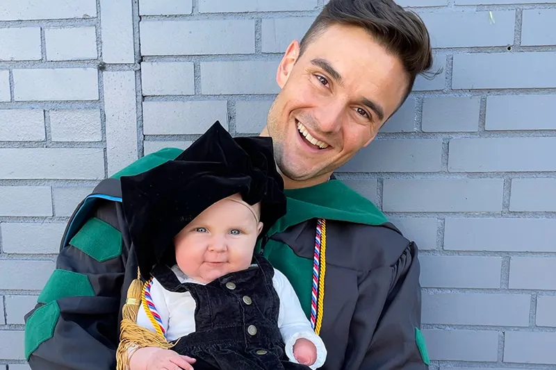 photo of Ethan and baby in front of brick wall. 