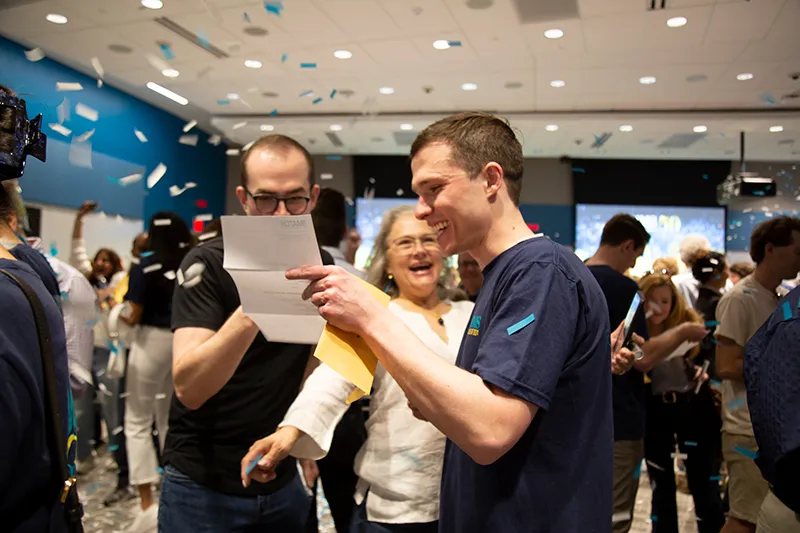students looking at a paper with confetti in the background