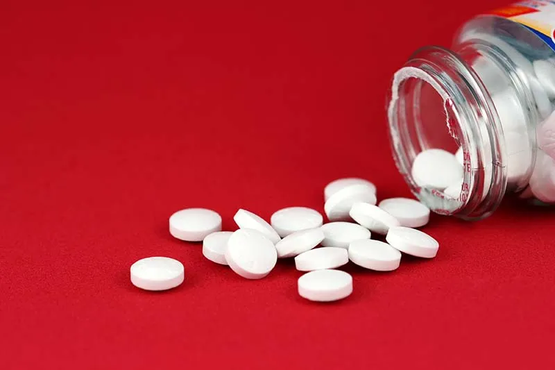 small white pills and a pill bottle 