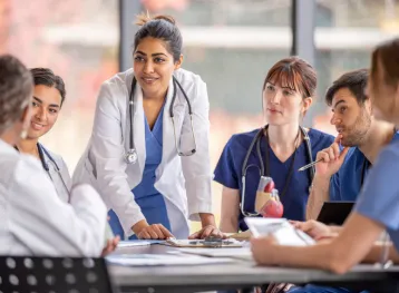 Medical professionals having a meeting in a private room sitting at a desk.