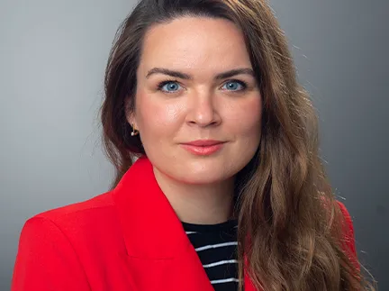 Alena Stewart poses for a professional headshot wearing a red business jacket.