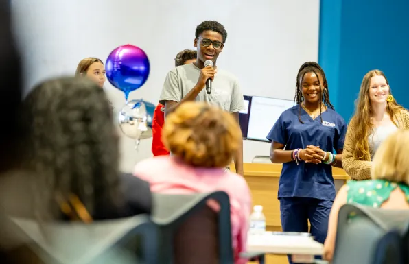 HSA students with balloons, giving a presentation with a microphone.