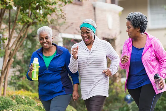 Three women walking on a suburban sidewalk in athletic clothing