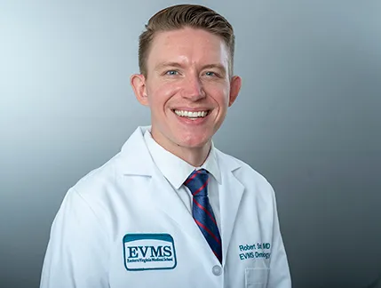 Robert Smith smiles at the camera wearing his white medical coat