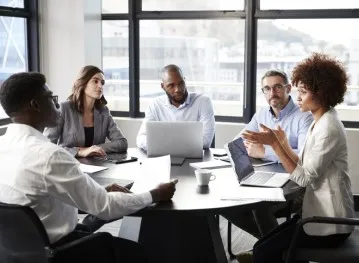 A group of diverse young professionals meet around a conference room table