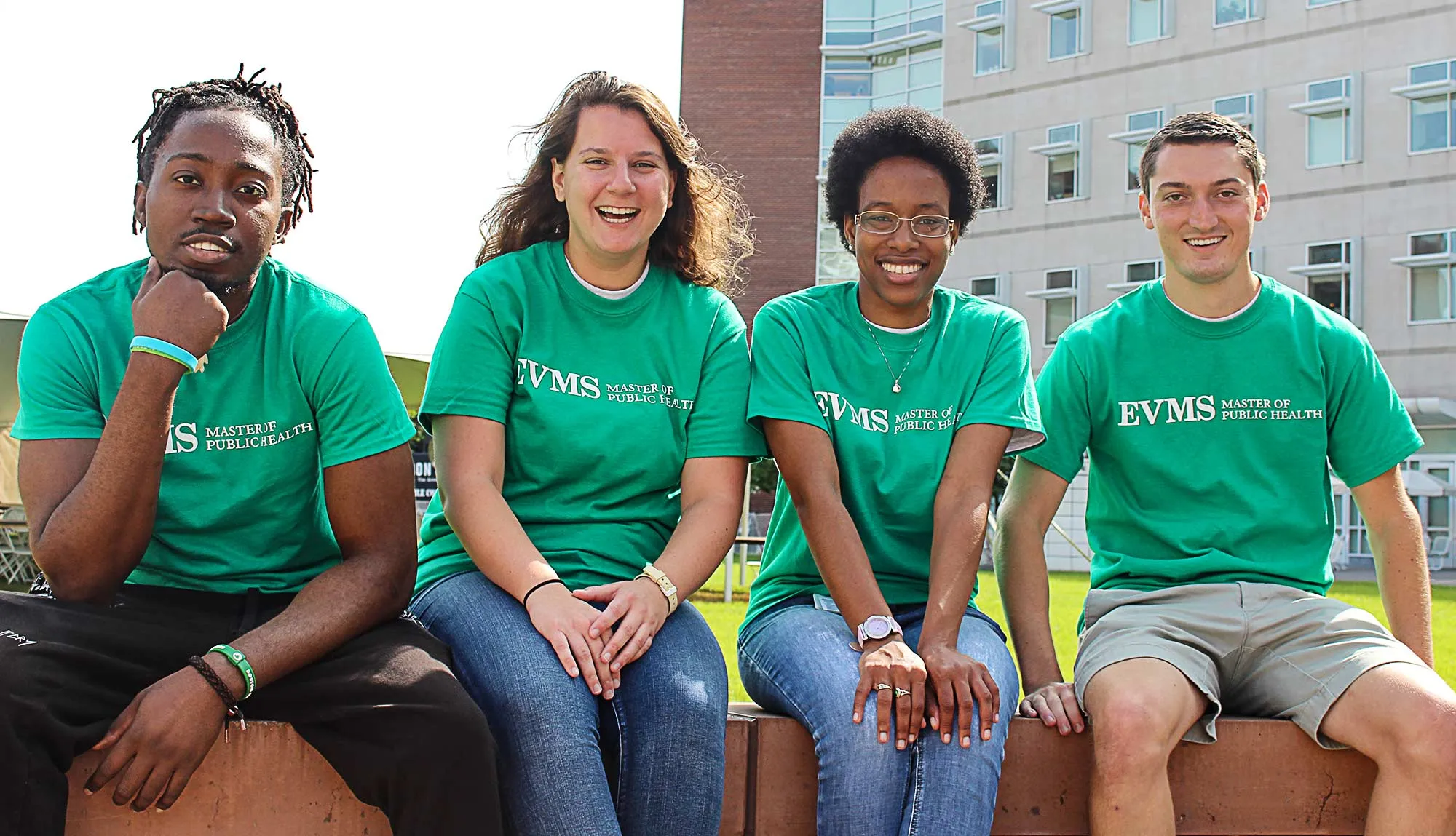 Master of Public Health students sit smiling outside Lewis Hall