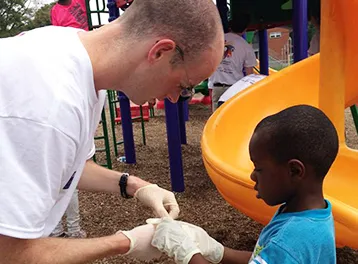 A student works with a child at a playground.