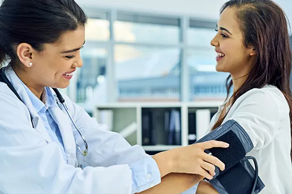 A fellow measures blood pressure for a patient with hypertension.