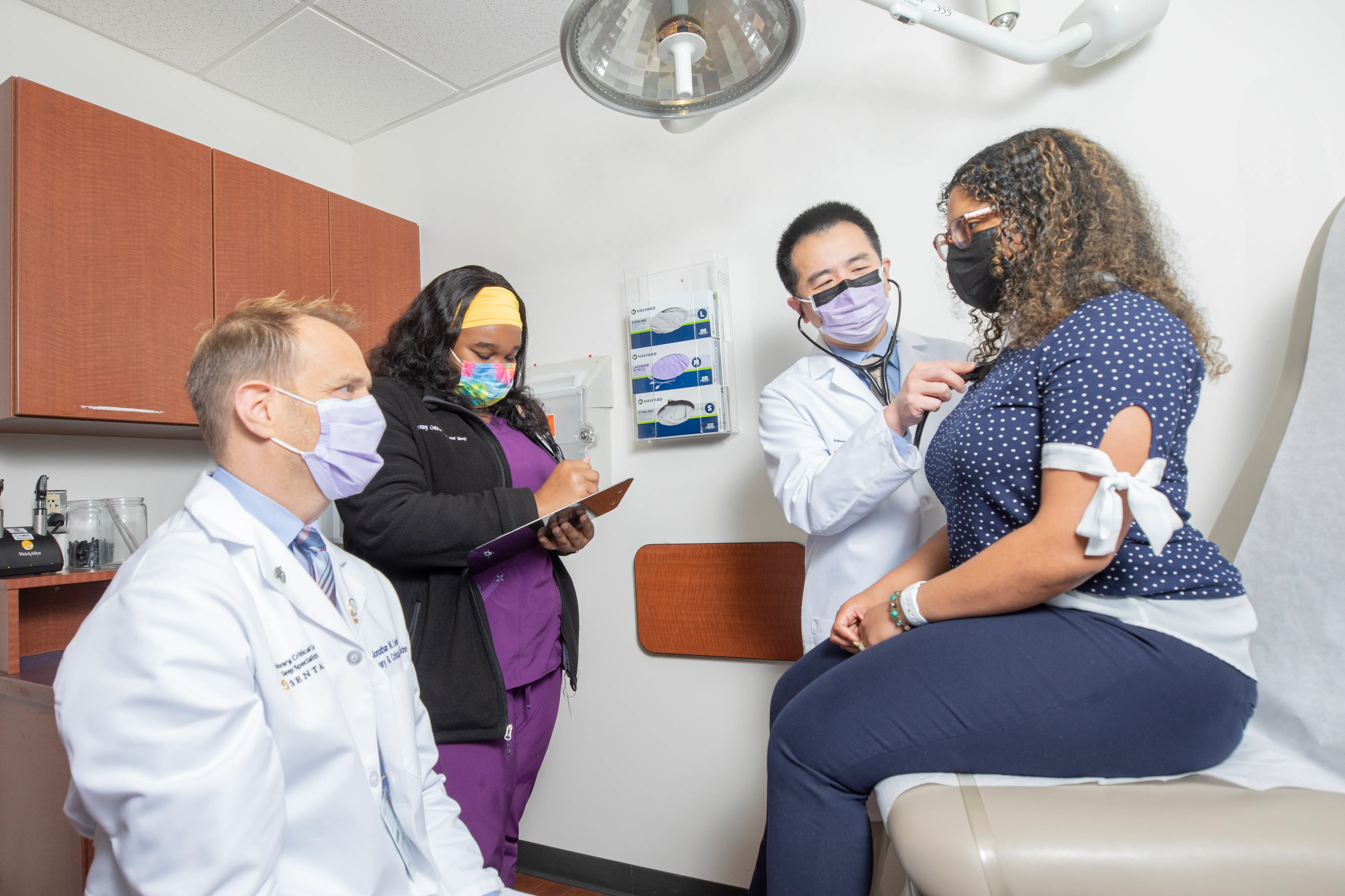 Three EVMS providers talking with a patient while one of them takes notes.
