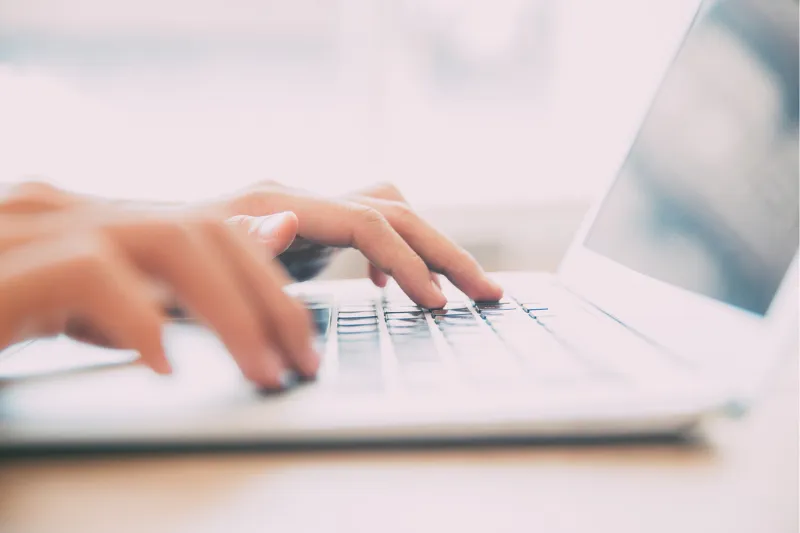 Hands typing on laptop