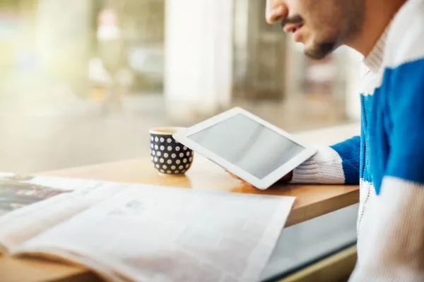 Partial profile of man with tablet and newspaper