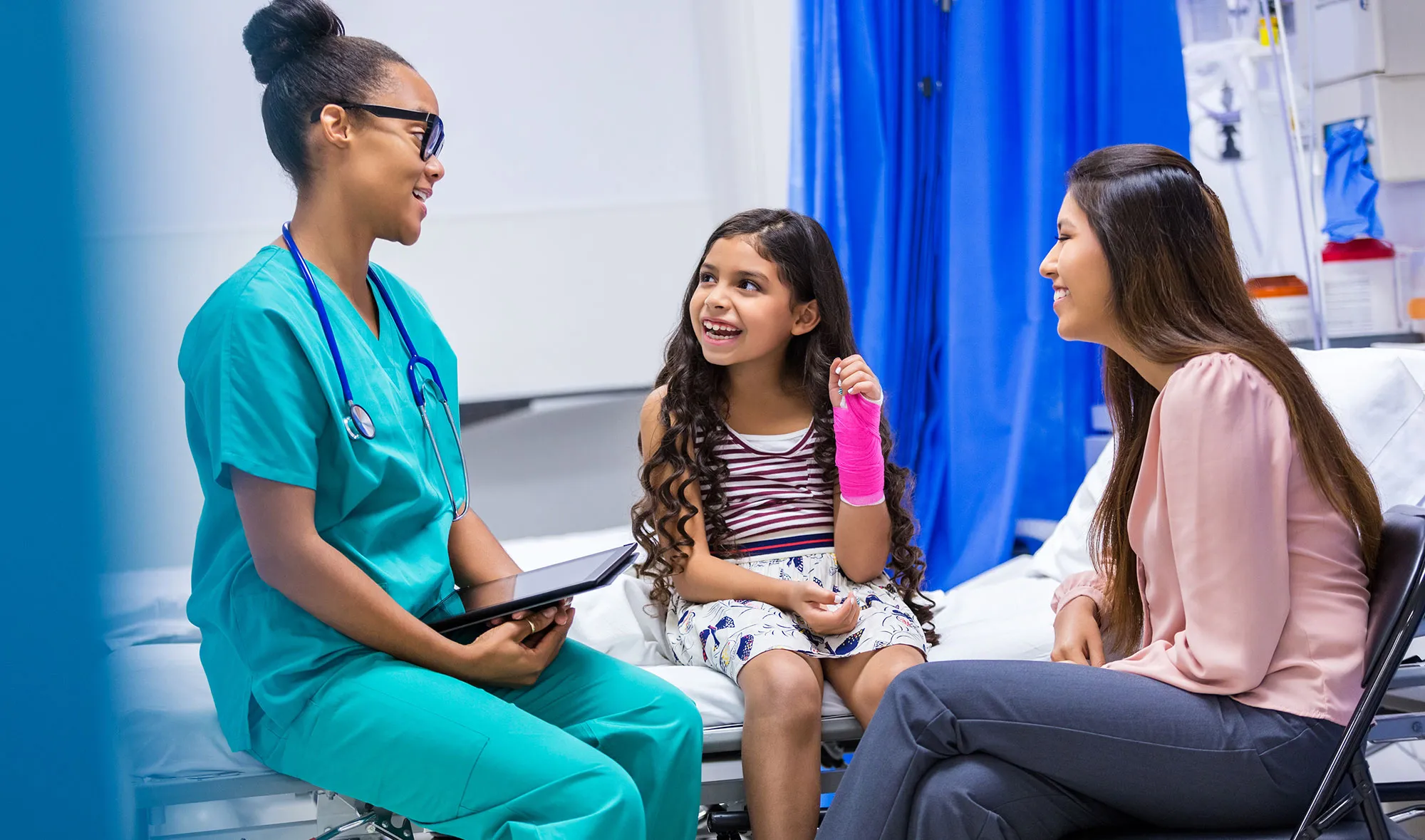 A fellow talks with a patient with a broken wrist and her mother.