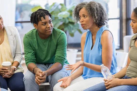 Group of parents listen to counselor discuss teenage issues.