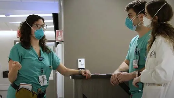 Anastasia Samaras, MD, a psychiatry resident, speaks to a male and a female medical student. All wearing masks.