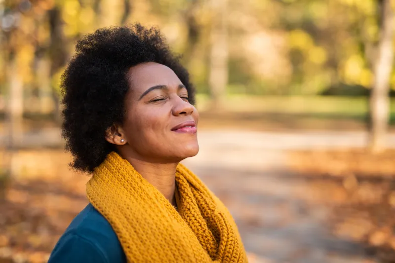 Woman smiling with fall leaves in background