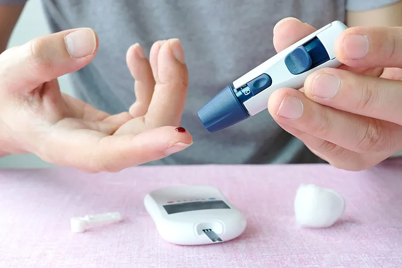 A patient uses a lancet to prick their finger for a blood glucose test.