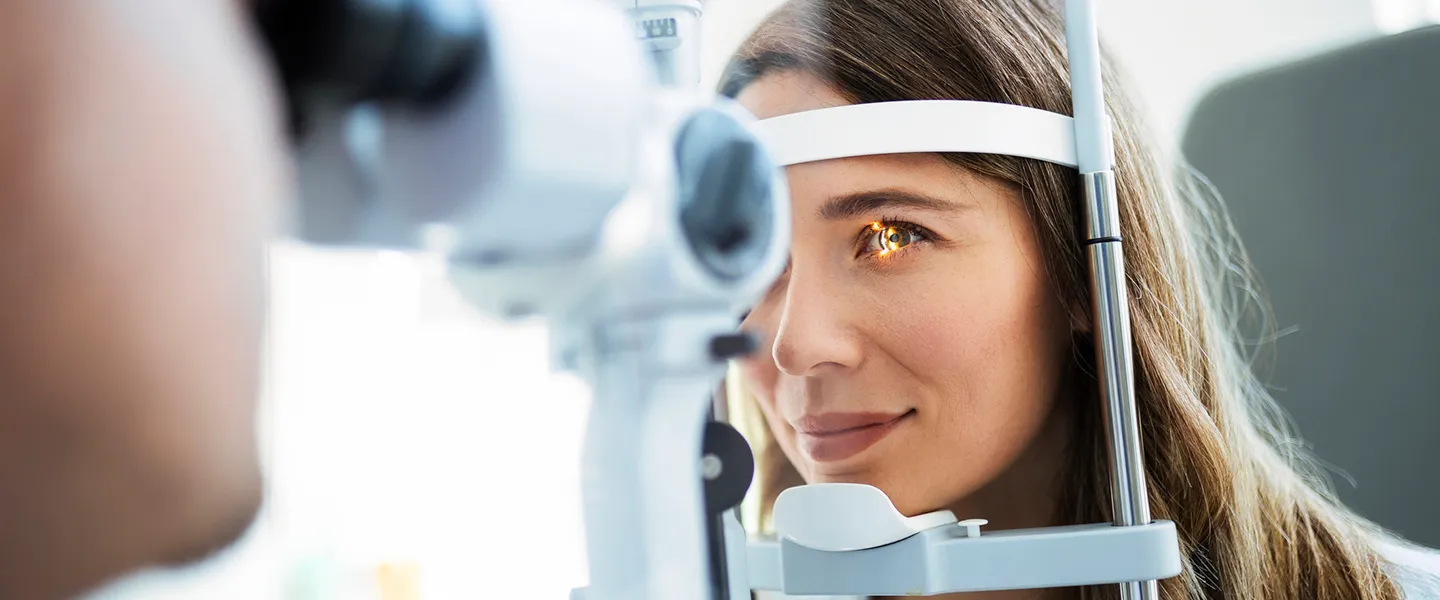 An ophthalmologist uses slit lamp to examine a woman’s eyes