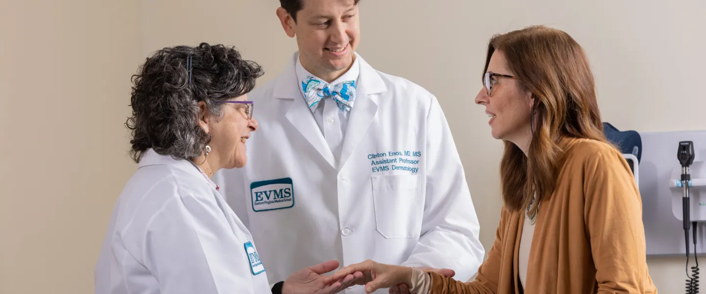 Dr. Van Voorhees and Dr. Enos looking at a patients hand for any skin conditions.
