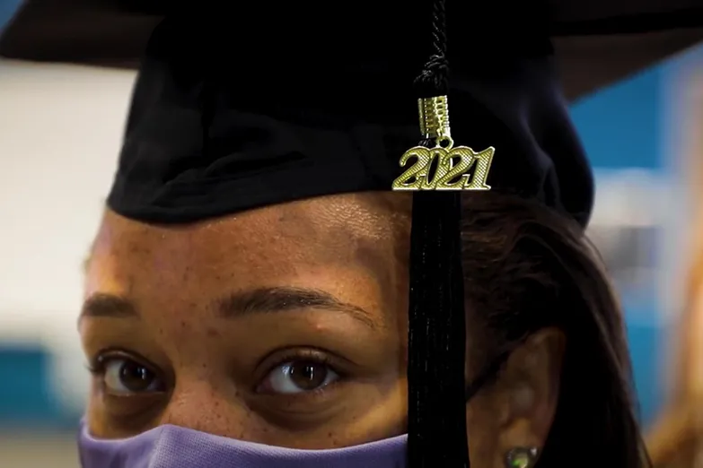 A student wearing a graduation cap with a 2021 charm