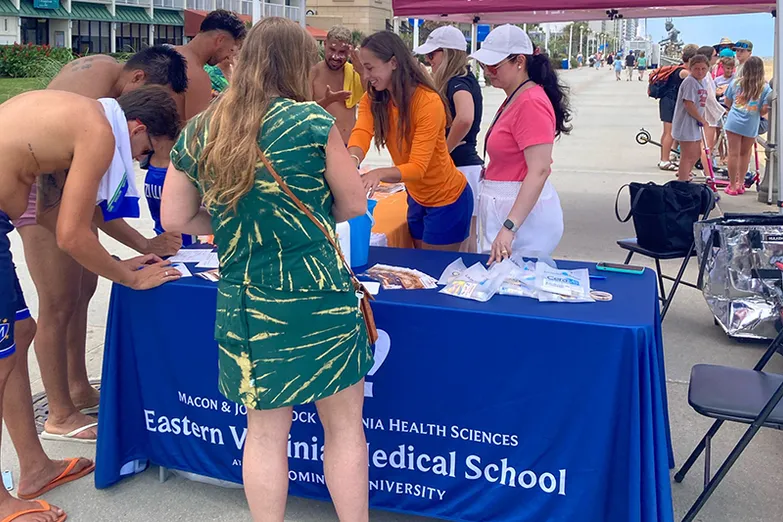 people under a tent handing out sunscreen.