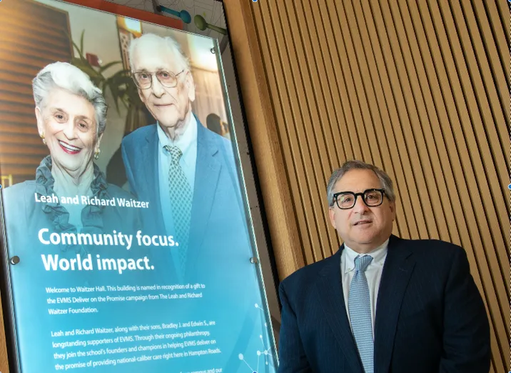 Brad Waitzer standing with a photo of Leah and Richard Waitzer