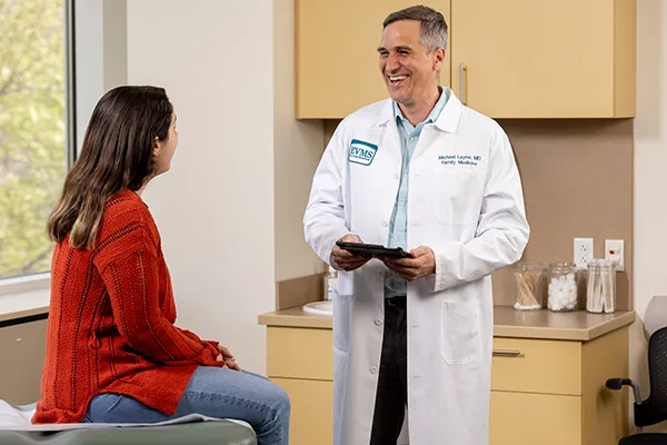 Dr. Layne with EVMS Ghent family medicine speaks with a patient in an exam room.